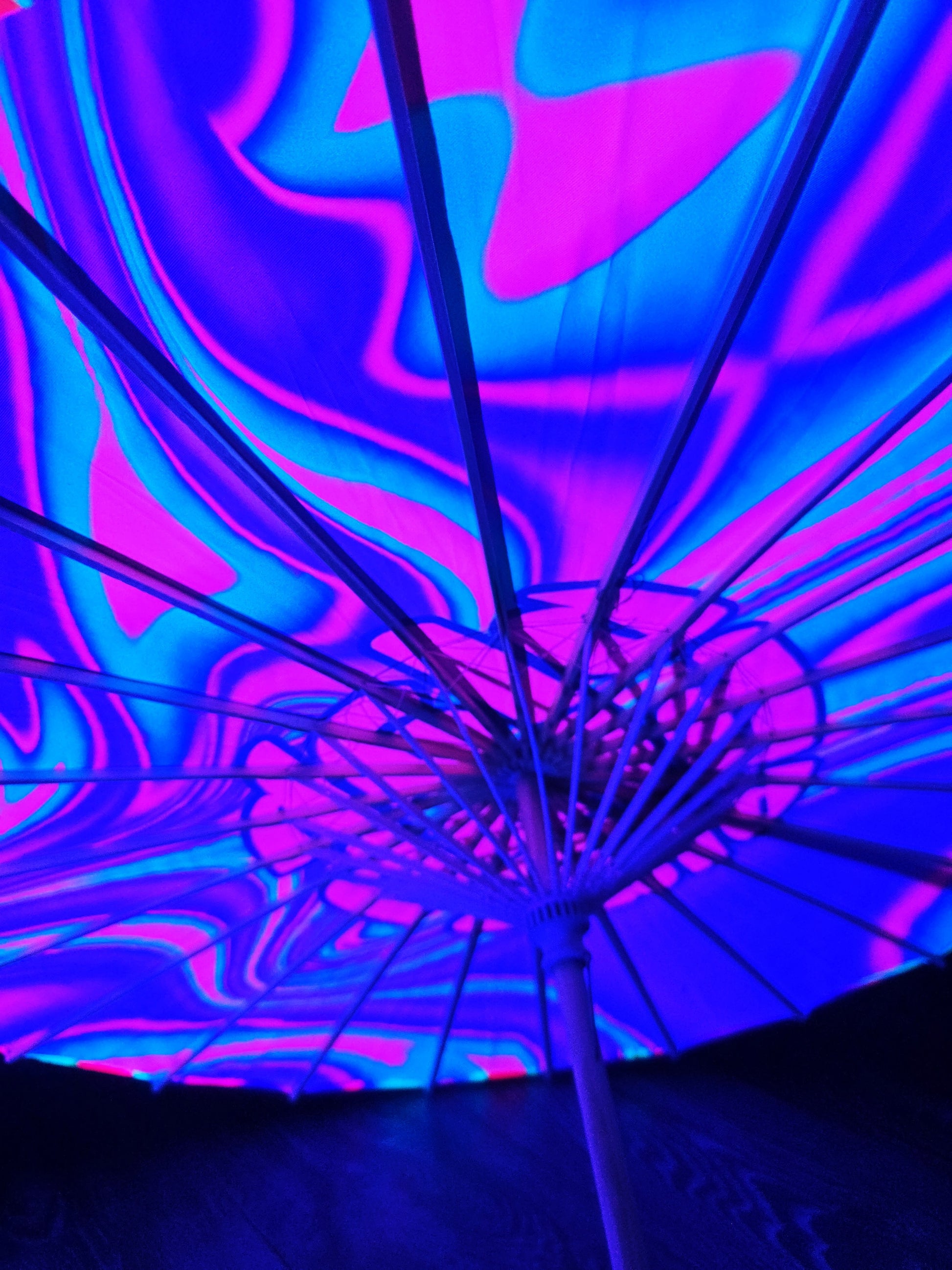 Glowing blue and pink abstract pattern on a dark background sun parasol that glows in the dark